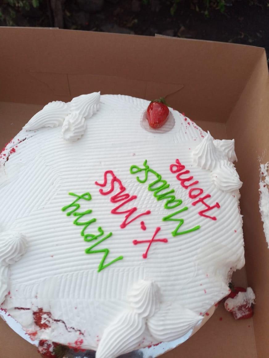 A white Christmas cake with a strawberry and red and green icing