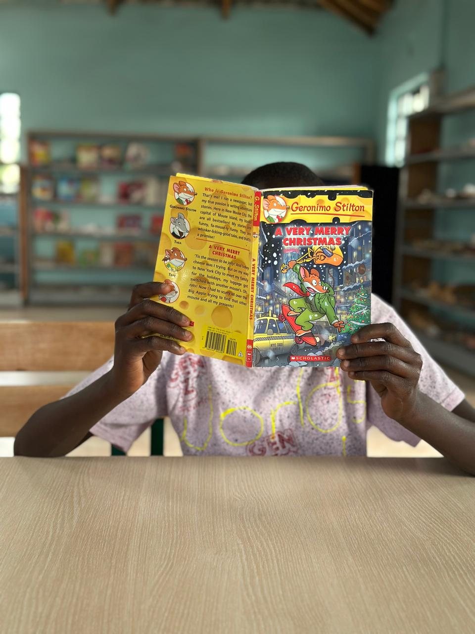 A child in the reading room holding up the storybook A Very Merry Christmas
