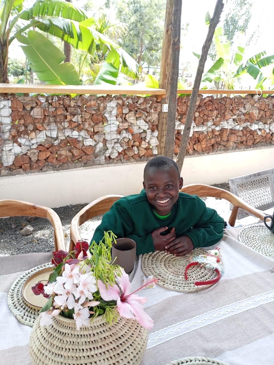 A smiling child at a table with fresh flowers