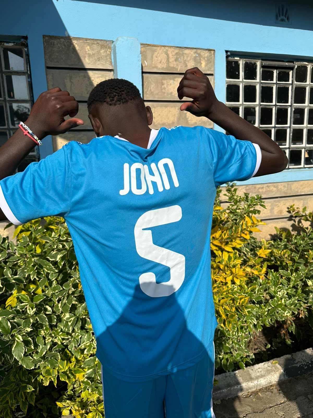 A player seen from behind pointing at the number 5 on his blue kit