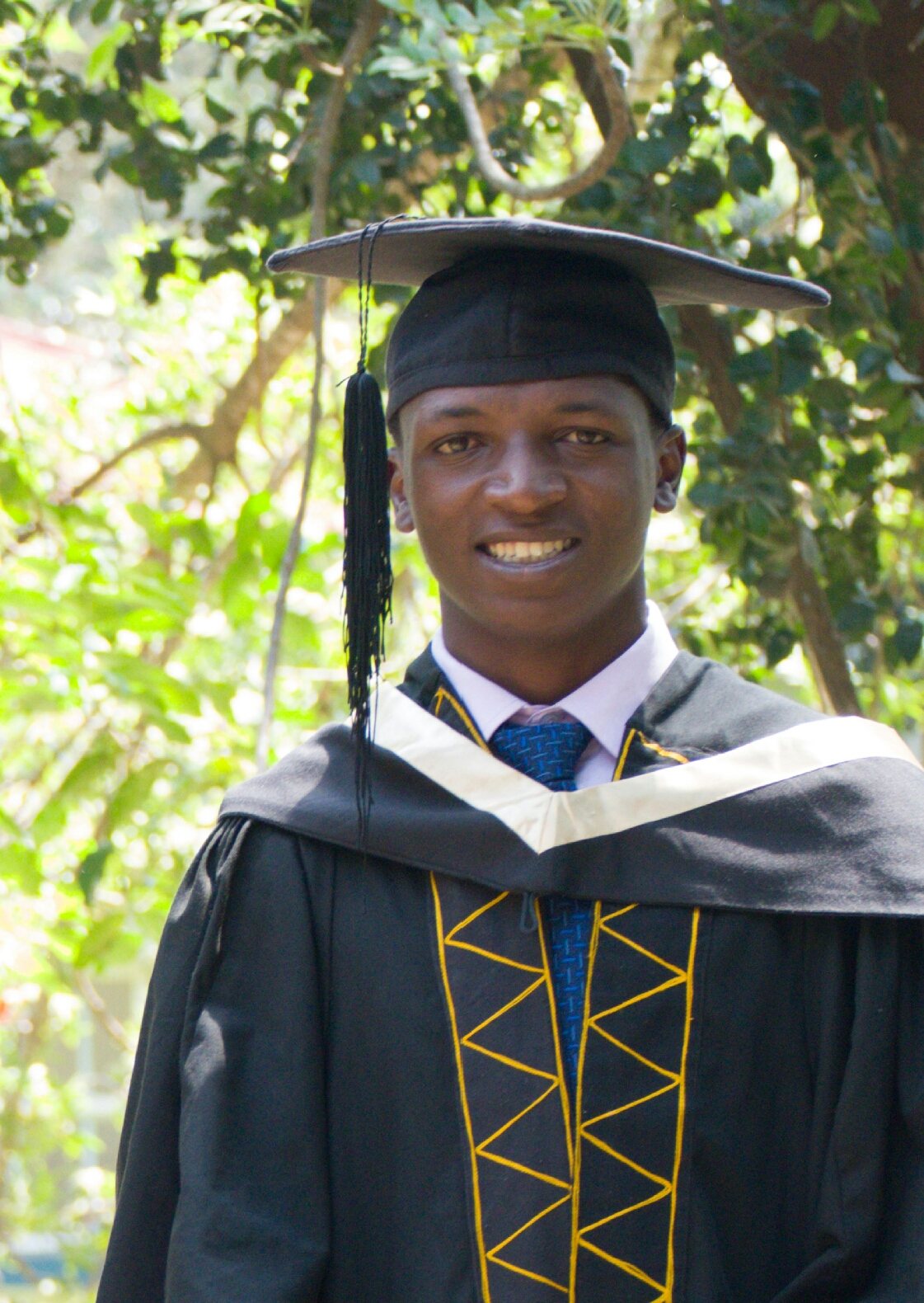 Edwin smiling in his graduation cap and gown