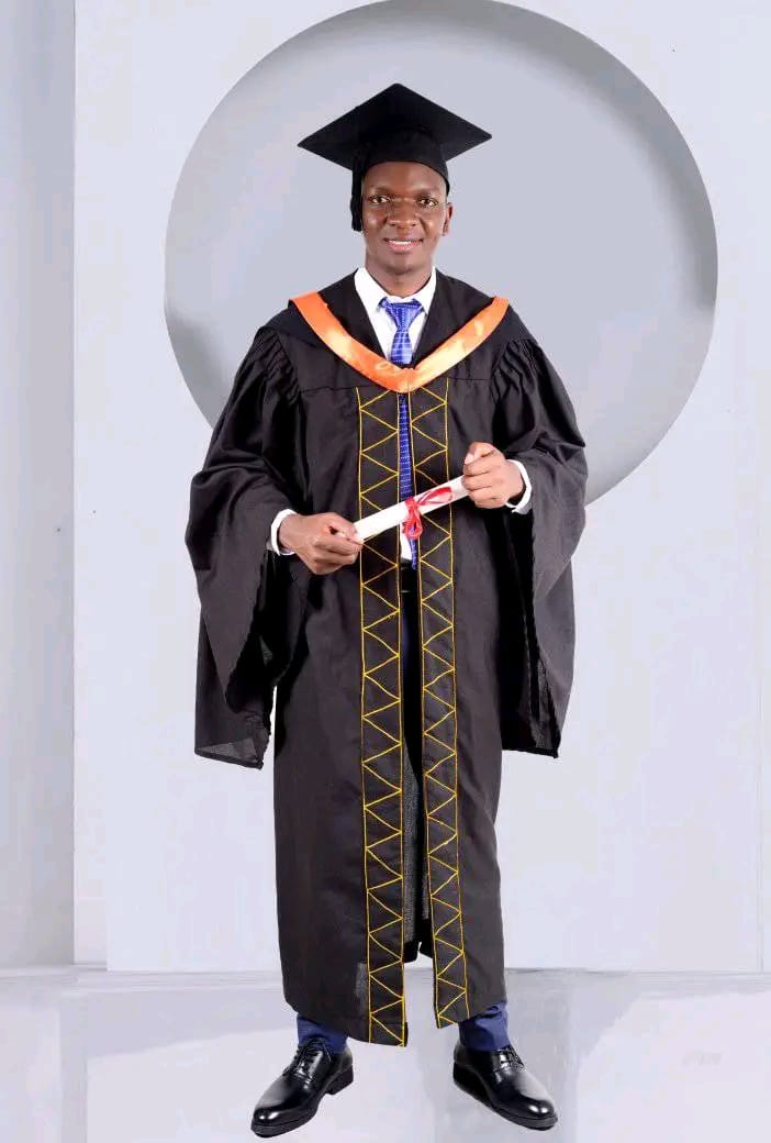 Elijah in graduation gown and cap holding his certificate