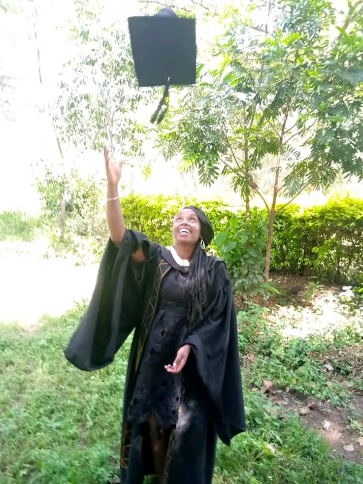 Esther celebrating her graduation by tossing her cap in the air