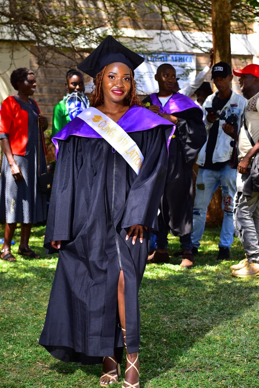 Roselyn in graduation cap and gown with a congratulations sash