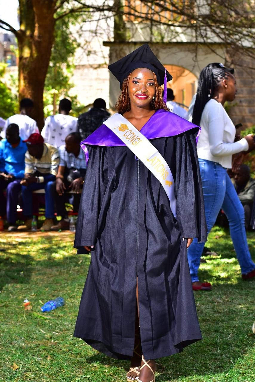 A graduate in cap, gown and congratulations sash