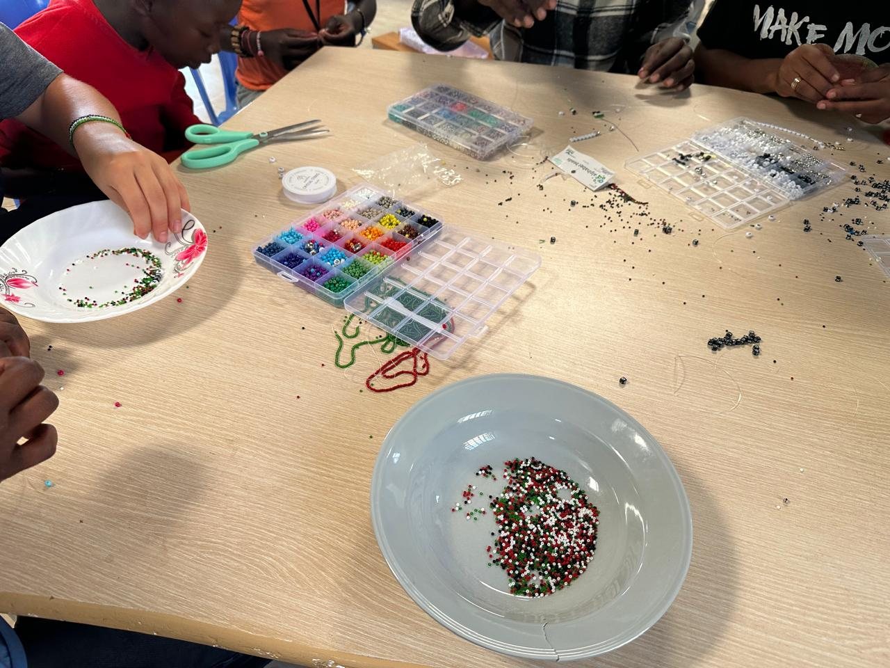 Trays of colourful beads and children threading bracelets
