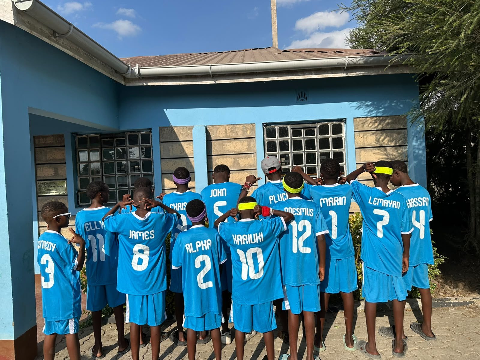 The whole team standing in a row with their backs to the camera, showing the numbers on their kits