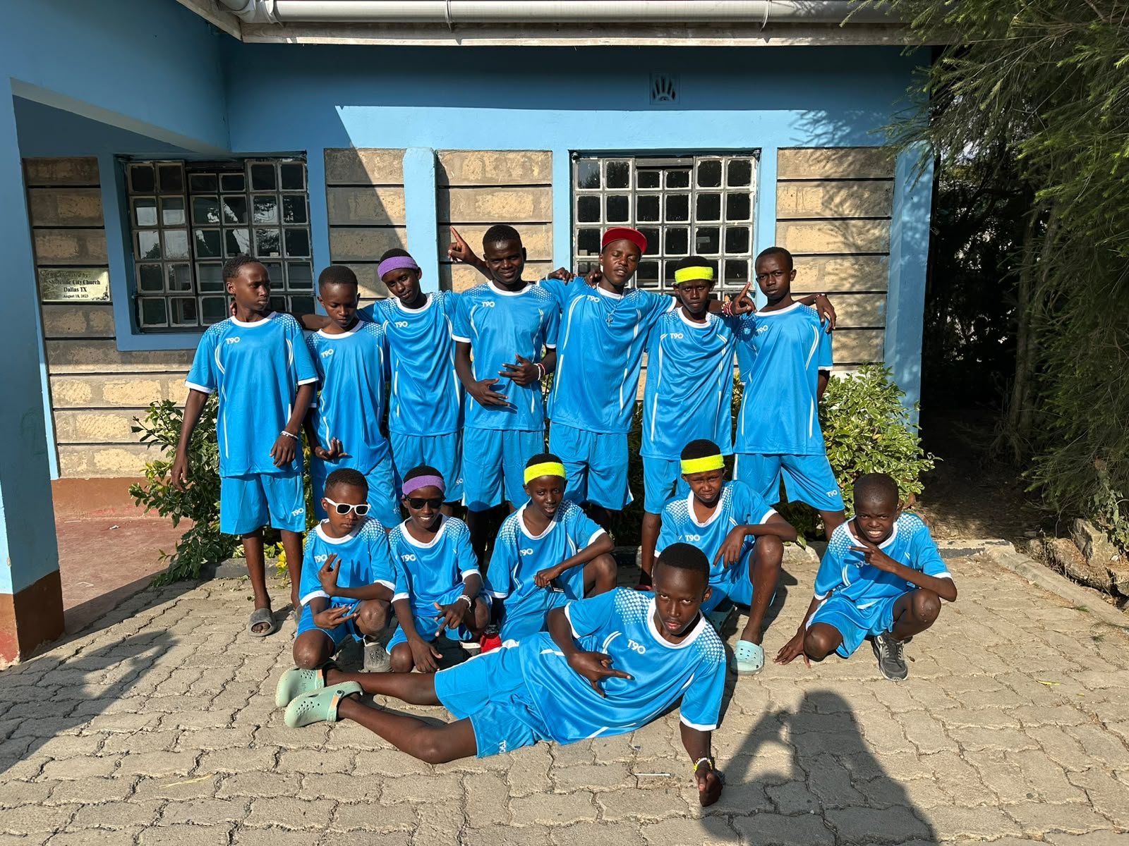 Boys of the SMCH Football Club posing in their blue kits outside the home